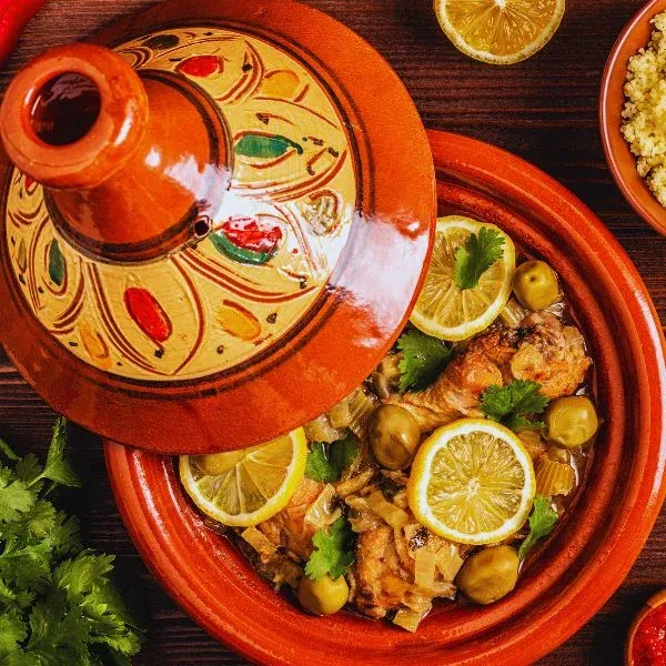 Tajine de poulet aux olives et rondelles de citron, couvercle peint posé à côté